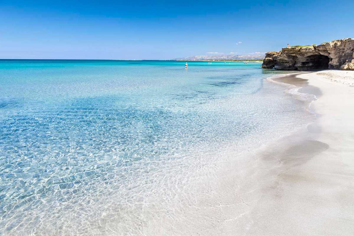 Spiaggia di Capri con acque cristalline e Faraglioni sullo sfondo