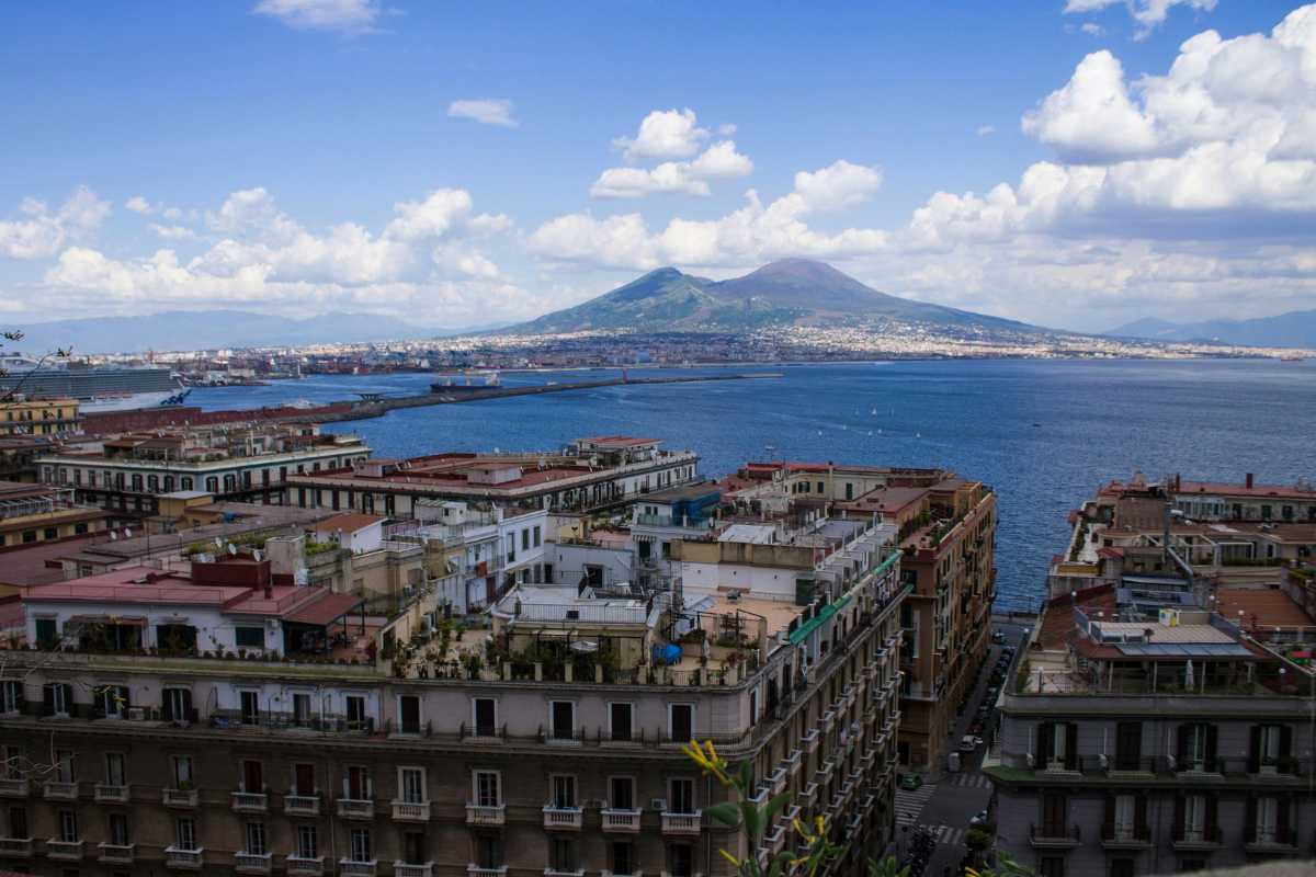 Una famiglia felice che esplora Napoli con i bambini, mostrando il centro storico e il Vesuvio sullo sfondo.